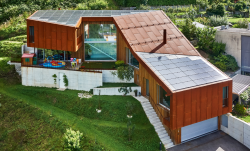 Das PEB-EFH Bottinelli-Croce in Cugnasco/TI mit seinen drei Fassadenelementen Holz, Metall und PV-Anlage bettet sich harmonisch in die Landschaft der Magadinoebene ein.