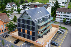 Südwestansicht des neu erstellten MFH Chrüzmatte in Aesch/LU. Es deckt mit dach- und dezent südwestlich fassadenintegrierten Solaranlagen 50% des Gesamtenergiebedarfs. 